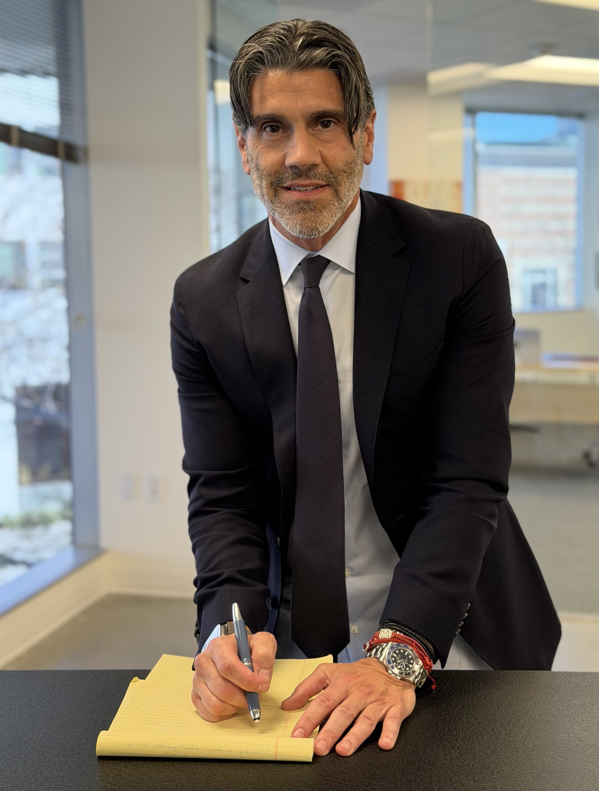 Man in a suit signing a document at a desk.